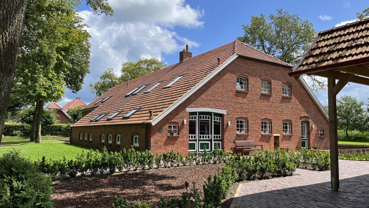 Das Landhaus mit überdachtem Terrassenbereich und Rasen