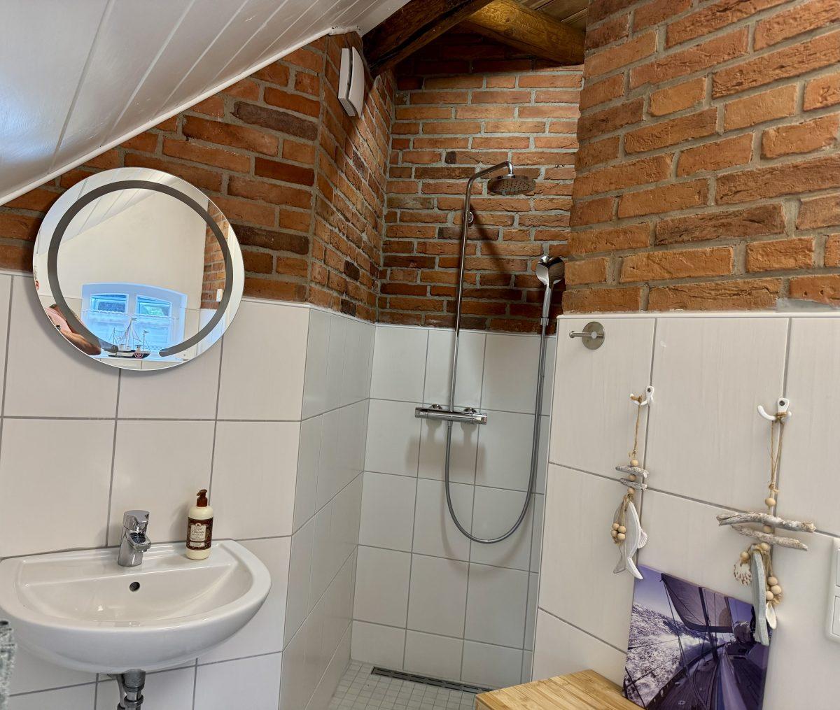 Badezimmer mit Dusche und rundem Spiegel
